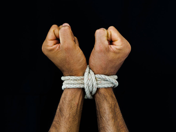 Man handen gebonden waren met een touw. Geweld, doodsbang, dag van de rechten van de mens concept. - Foto, afbeelding