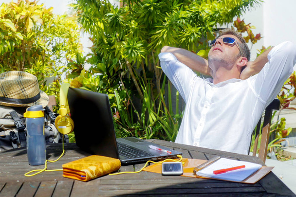 young attractive and happy digital nomad man working outdoors from coffee shop with laptop computer leaning back relaxed and confident in traveler and business travel lifestyle concept - Photo, Image