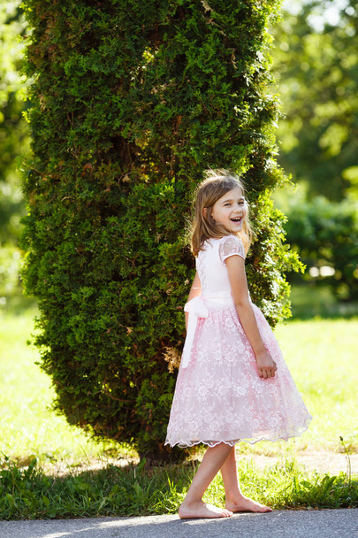 Retrato de uma menina alegre em um vestido rosa exuberante no parque no pôr do sol
. - Foto, Imagem