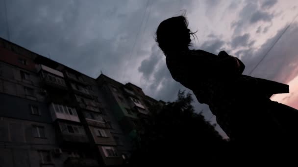 Silhouet van een meisje tegen de achtergrond van een blok van flats. Diepe emotionele trauma en ervaring. - Video