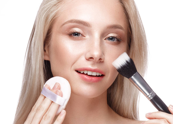 Beautiful young girl with a light natural make-up, brushes for cosmetics and nude manicure. Beauty face. - Photo, Image