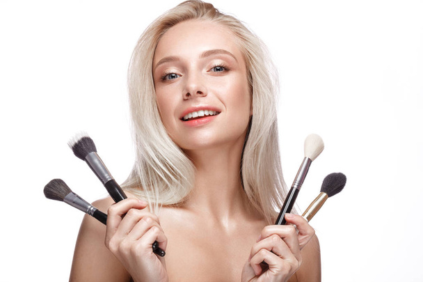 Beautiful young girl with a light natural make-up, brushes for cosmetics and nude manicure. Beauty face. - Foto, Imagem