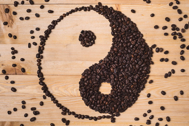 Ying yang καφέ σύνθεση με ψημένα φασόλια καφέ κατανέμονται στο τραπέζι από ξύλο - Φωτογραφία, εικόνα