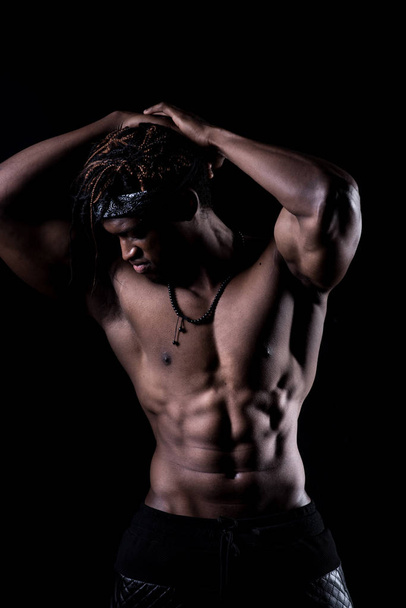 Young afro american sports man with beautiful muscular body on black background - Φωτογραφία, εικόνα