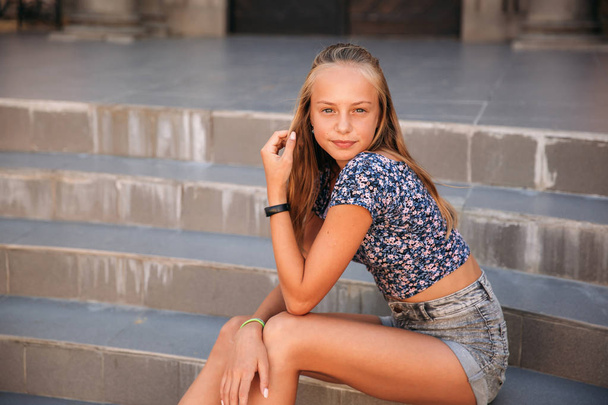 teenage female dressed in jeans sits on stairs - Photo, Image