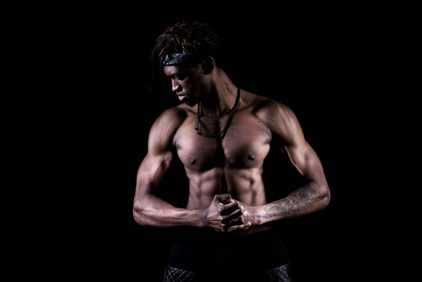 Студийный снимок мускулистого афро-американца, позирующего на черном фоне
 - Фото, изображение