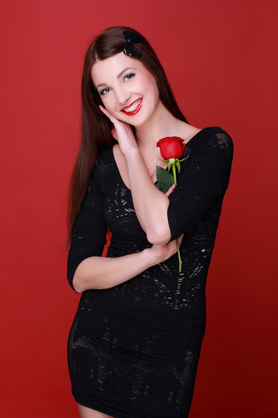 κορίτσι με ένα τριαντάφυλλο σε κόκκινο φόντο - Φωτογραφία, εικόνα