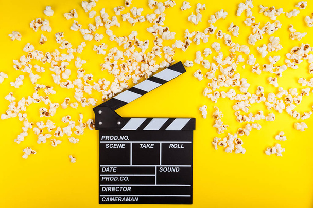Sfondo cinematografico. Guardare film. Popcorn e clapperboard su sfondo giallo vista dall'alto copia spazio
 - Foto, immagini