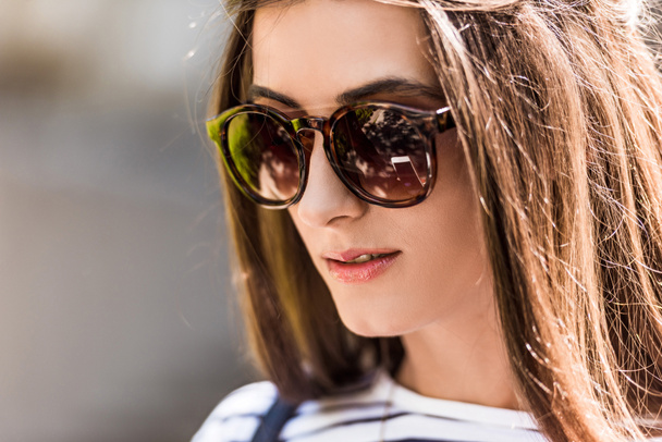 portrait of of beautiful young woman in sunglasses on street - Fotó, kép