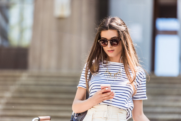 portrait de jeune femme séduisante dans les écouteurs en utilisant smartphone sur la rue
 - Photo, image