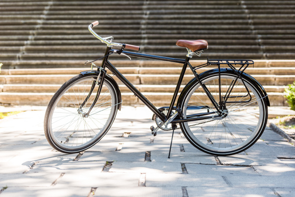 lähikuva näkymä kadulle pysäköidylle mustalle polkupyörälle
 - Valokuva, kuva