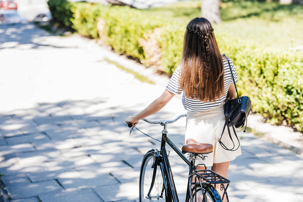 Widok kobiety z powrotem z retro rower spaceru na ulicy - Zdjęcie, obraz