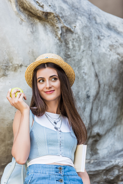 portrait of young stylish woman in hat with fresh apple on street - Zdjęcie, obraz