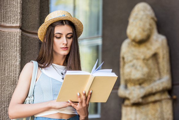 portrait of student in straw hat reading book on street - Photo, Image