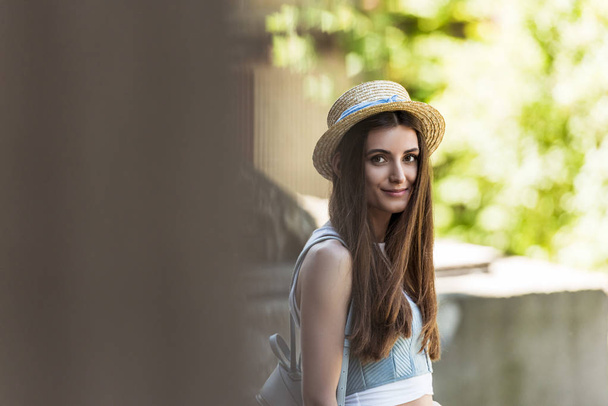 side view of beautiful woman with long hair in straw hat on street - Foto, Imagen