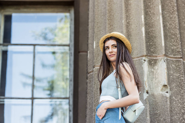 side view of young beautiful woman in straw hat on street - Foto, afbeelding