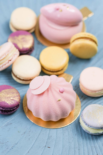 ピンクのムースケーキ。青緑色の背景にフランス マカロンのデザートと花のユーカリ。パステル カラー - 写真・画像