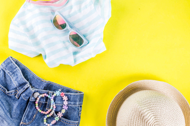 Концепція літніх канікул, літній комплект дитячого одягу - дитячі шорти, футболка, капелюх, сонцезахисні окуляри, браслет намисто, кросівки, яскраво-жовтий фон над плоским місцем для копіювання
 - Фото, зображення