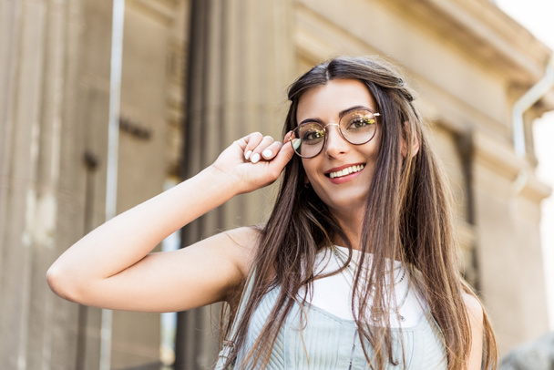 portrait of attractive smiling woman in eyeglasses on street - Zdjęcie, obraz