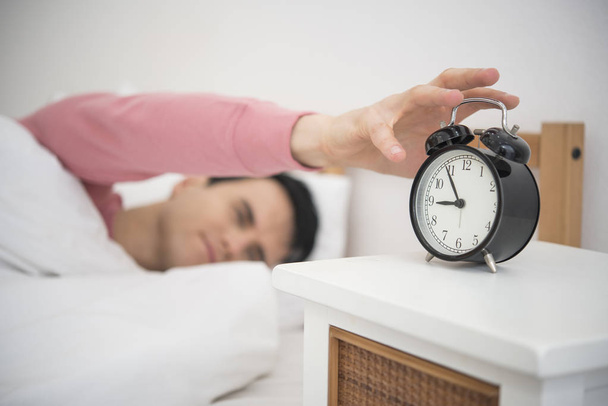 Man wake up doing turn off alarm clock in the morning. He tired and lazy do work. - Photo, Image