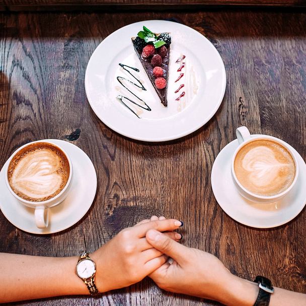 Primer plano manos femeninas y masculinas sosteniendo en el fondo de la mesa de café
 - Foto, imagen