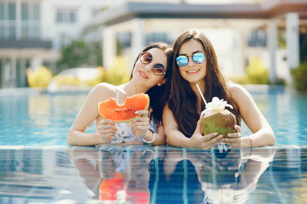 two girls tanning and having fruit by the pool - Фото, изображение