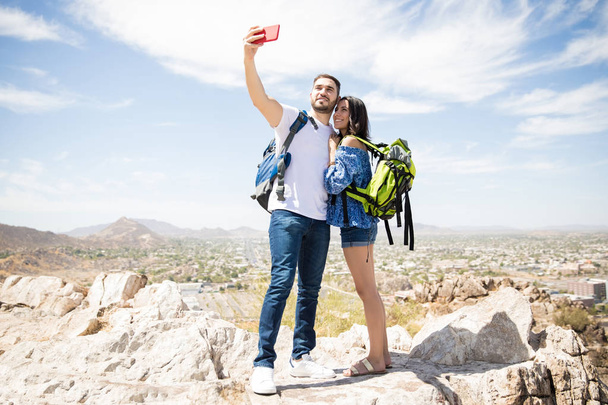 Чарівна туристична жінка і чоловік в горах роблять селфі використовує мобільний телефон
 - Фото, зображення