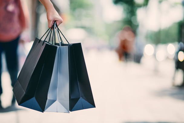 Primer plano de la mano de la mujer sosteniendo bolsas de compras mientras camina por la calle
. - Foto, Imagen