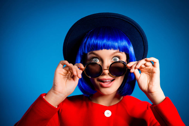 Sale! Head shot portrait of stupid impressed girl with wide open eyes unexpected reaction looking out summer glasses isolated on blue background. Delight concept - 写真・画像
