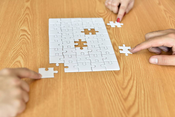 Closeup of businessman and woman with jigsaw puzzle pieces in office.Finally finding solution.puzzle piece coming down into it's place - Photo, Image