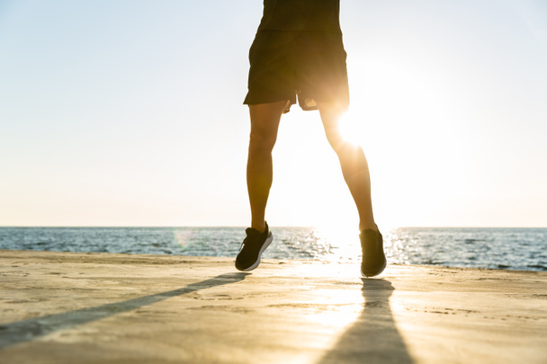 komea aikuinen urheilija hyppää meren rannalla
 - Valokuva, kuva