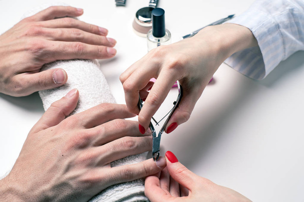 Manicura masculina. mujer esteticista trata cutículas de manos masculinas secas
 - Foto, imagen