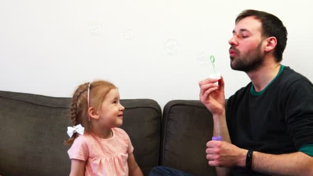 A little girl catches soap bubbles by her mouth in slow motion. A father and his daughter spend time together. - Footage, Video