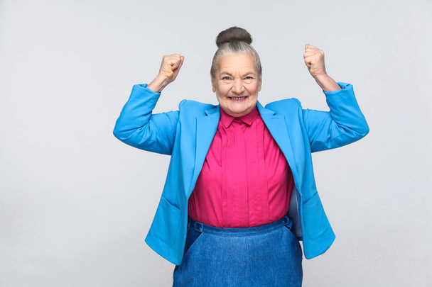 Ευτυχισμένος επιτυχημένη γυναίκα που φοράει το μπλε κοστούμι και ροζ πουκάμισο πανηγυρισμούς νίκη, έκφραση συναισθημάτων και συναισθήματα έννοια    - Φωτογραφία, εικόνα