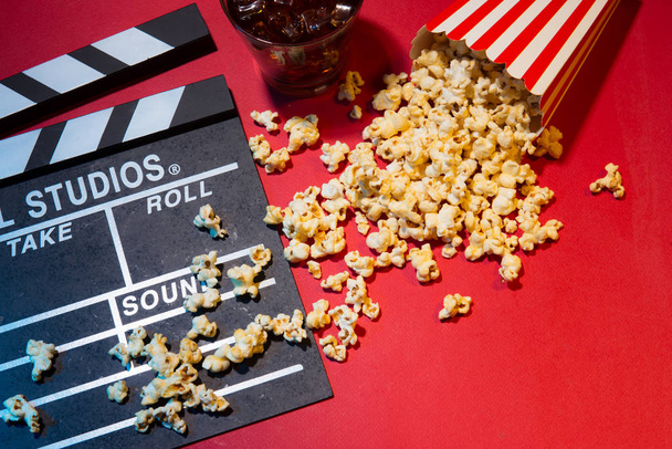 Cinema concept. Clapperboard, ticket and popcorn on red background - Photo, Image