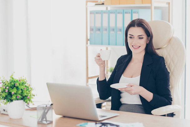 Portrait of cheerful charming woman having coffee break watching film video movie sitting at desk in modern workplace - Фото, зображення