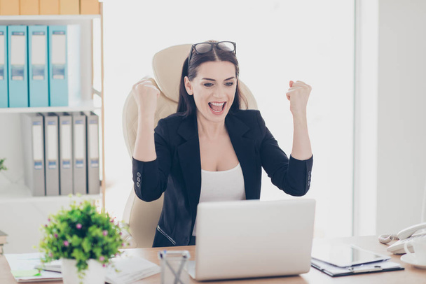 Portrait of cheerful positive attorney holding hands up yelling celebrating big effective results great triumph getting inspiration motivation clenches fists sitting at desktop in modern work place - Foto, Bild