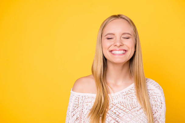 Portrait with copy space empty place of comic funky girl laughing with clenched teeth keeping eyes closed isolated on yellow background - Fotoğraf, Görsel