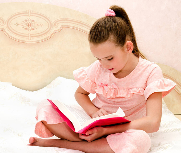 Rozkošný dívka dítě čte knihu na postel - Fotografie, Obrázek