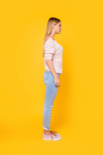 Full size fullbody profile side view portrait of charming pretty girl wearing pants shoes isolated on bright vivid yellow background - Foto, afbeelding