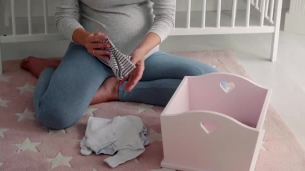 Unerkennbare Schwangere beim Einpacken von Babykleidung - Filmmaterial, Video