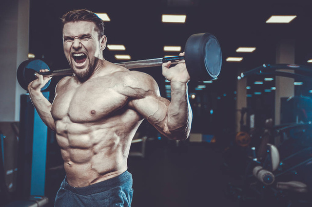 Handsome young fit muscular caucasian man of model appearance workout training in the gym gaining weight pumping up muscle and poses fitness and bodybuilding sport nutrition concept - Fotoğraf, Görsel