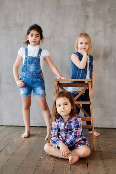 three girls with wooden chair posing on  concrete wall background  - Foto, immagini