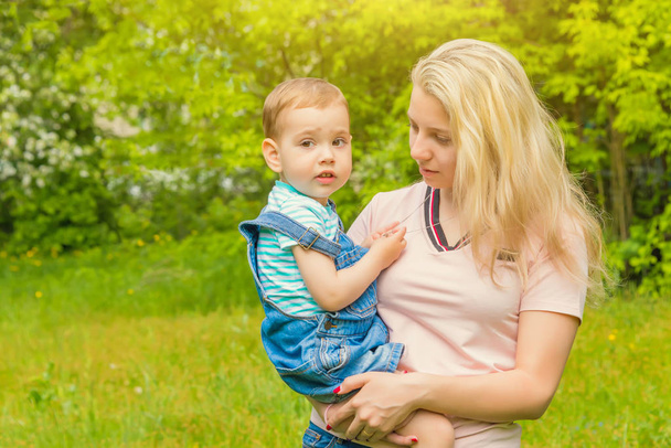 mother and child in nature in the Park, resting on the green grass in Sunny weather, happy family - Фото, зображення