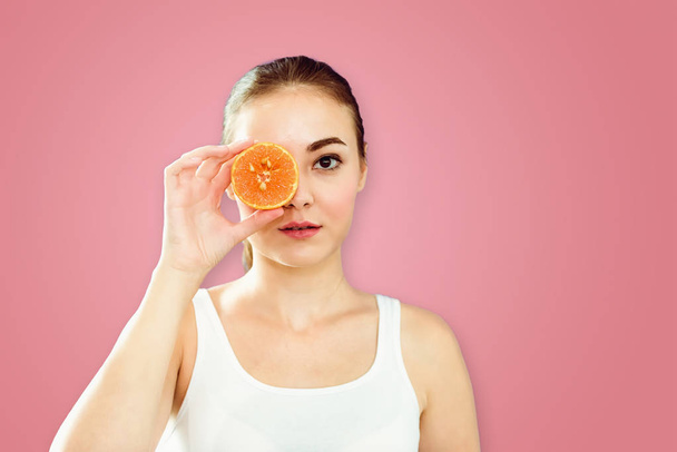 Portrait of young woman showing an orange beside her eyes on isolate background., Healthcare, Diet concept . - Fotografie, Obrázek