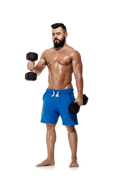 muscular man doing exercises with dumbbells. - Photo, Image