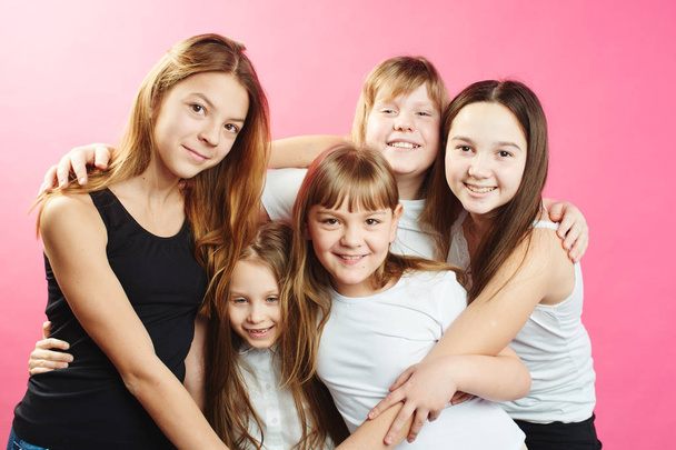 group of cute girls hugging while posing on pink background - Фото, зображення