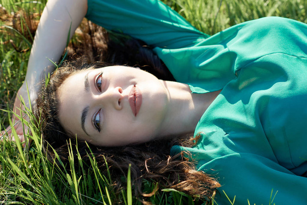 menina bonita deitada na grama no dia ensolarado, close-up rosto, floresta de verão, paisagem brilhante com sombras
 - Foto, Imagem