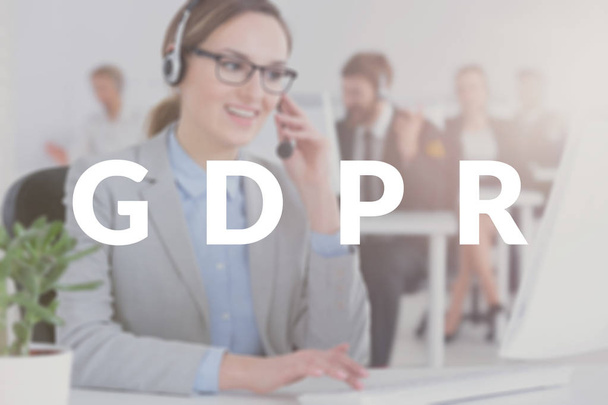 Call center employee talking to customers about the personal information her company collects. Blurred photo with white GDPR banner - 写真・画像