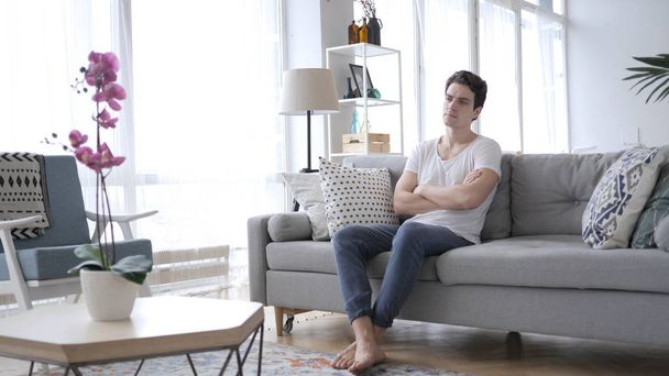 Серьезный расслабляющий мужчина сидит дома на диване
 - Фото, изображение